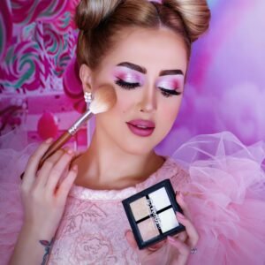 Vibrant portrait of a woman applying makeup with a pink theme and elegant hairstyle.